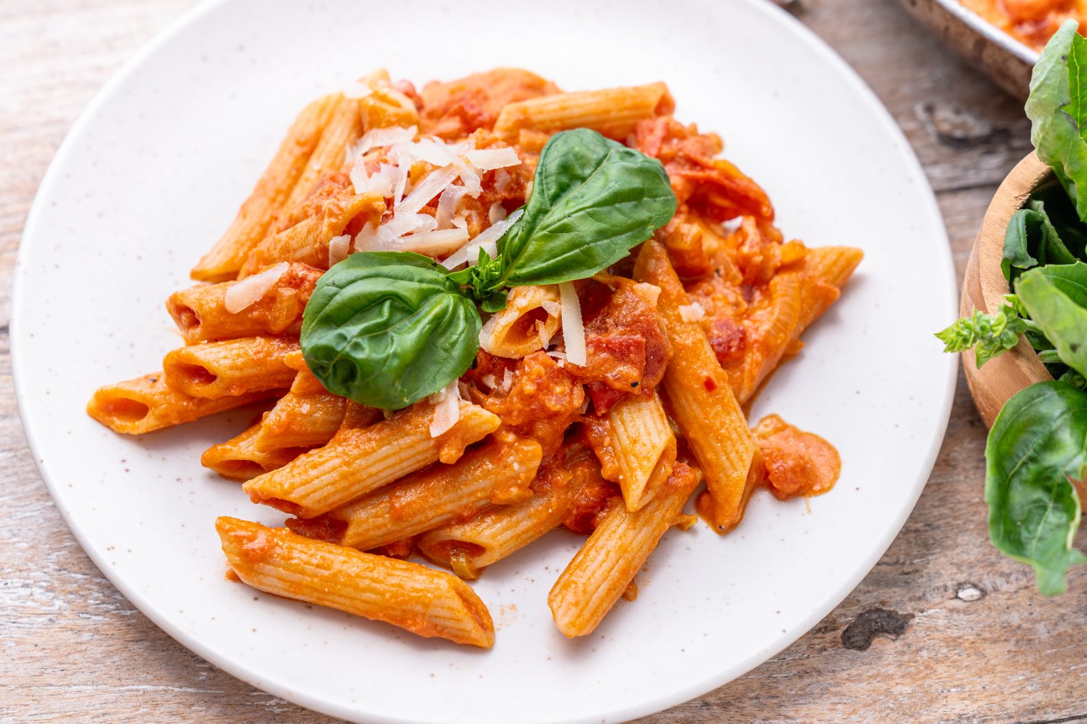 vodka sauce and penne pasta topped with basil on a plate