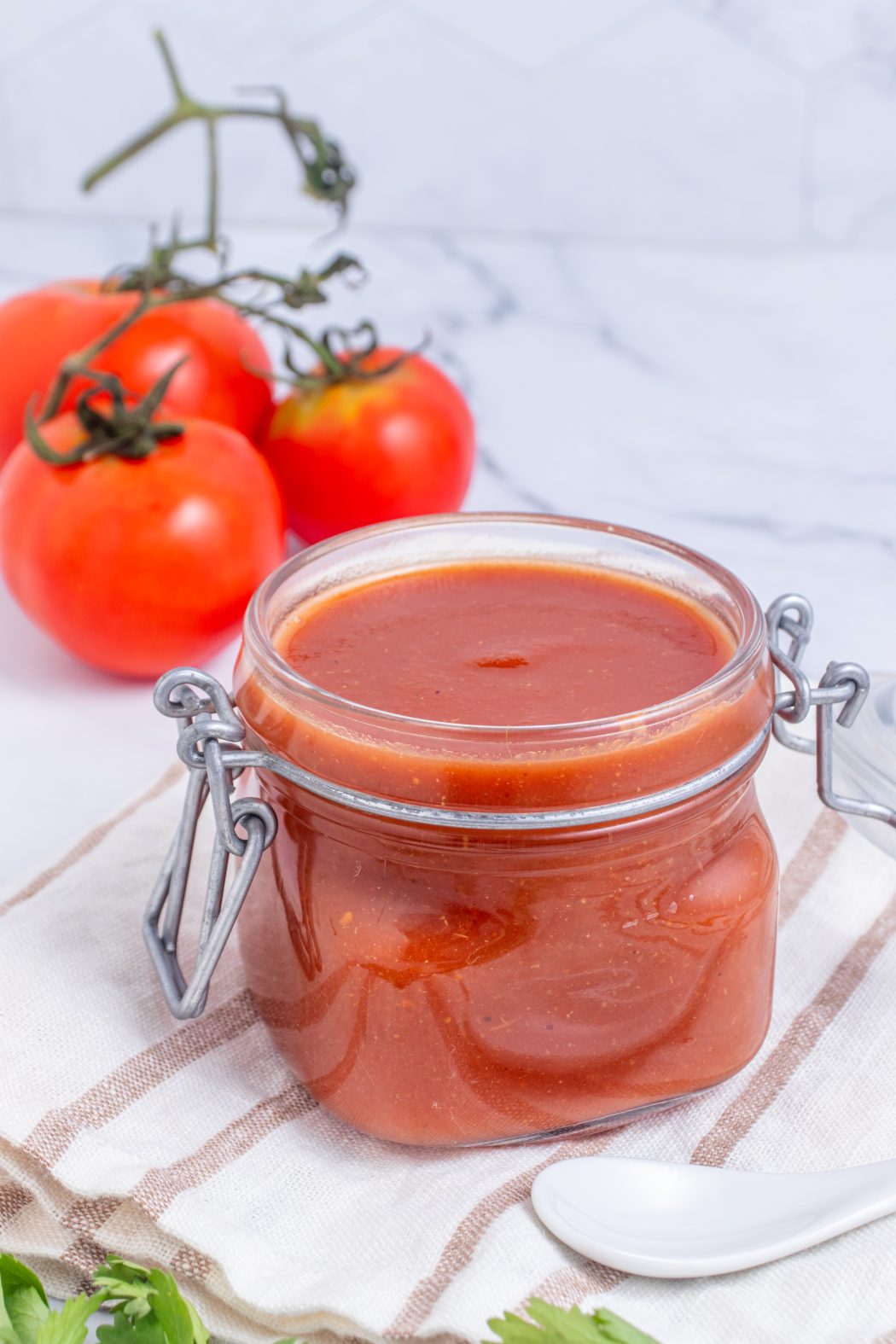 roasted tomato salsa in a jar with fresh tomatoes in the background