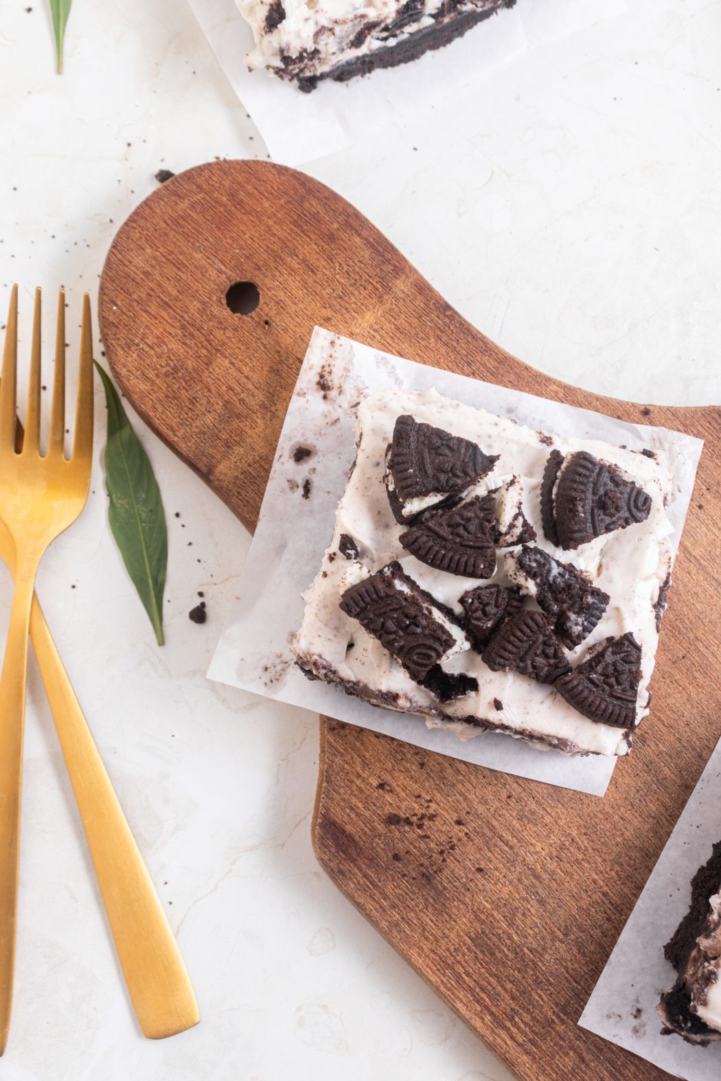 Oreo Cheesecake bars on a cutting board with a gold fork