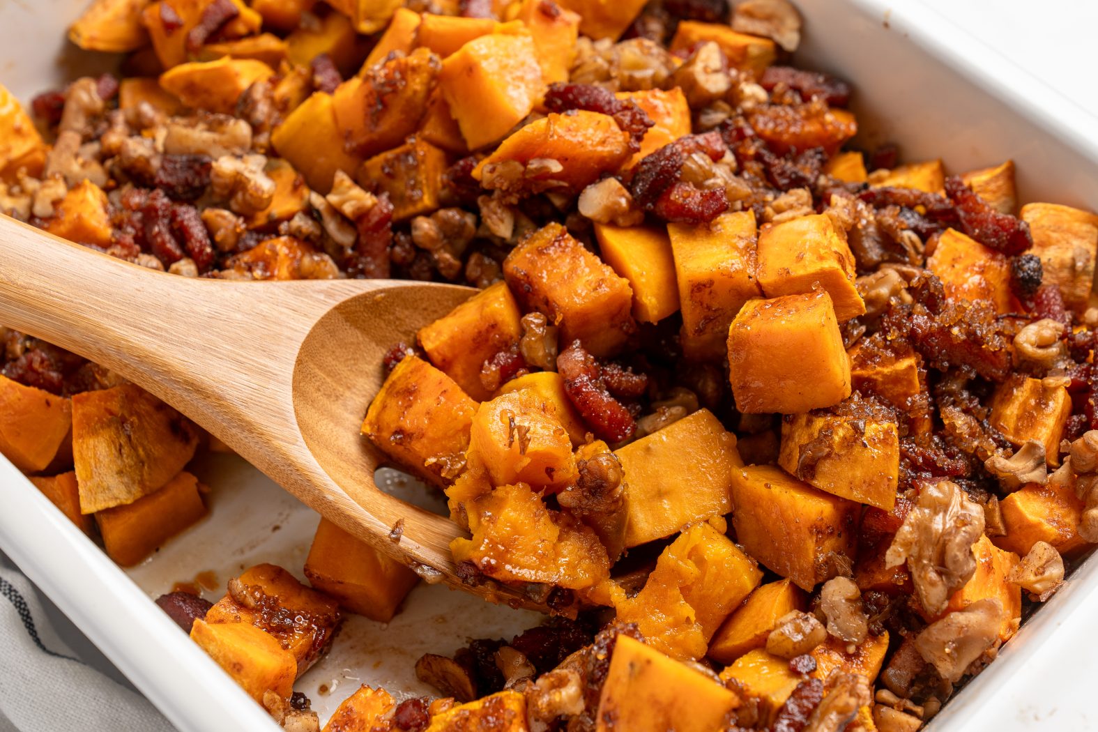 Wooden spoon scooping out sweet potato casserole