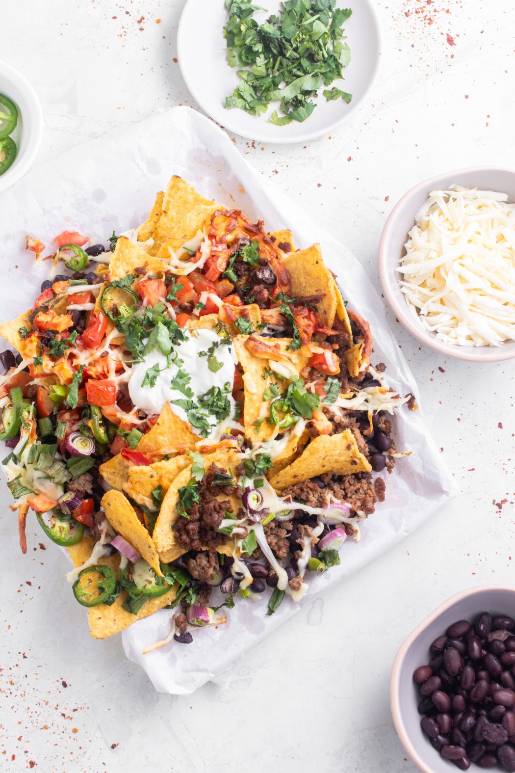 Top view of a plate of air fryer nachos and a bowl of shredded cheese