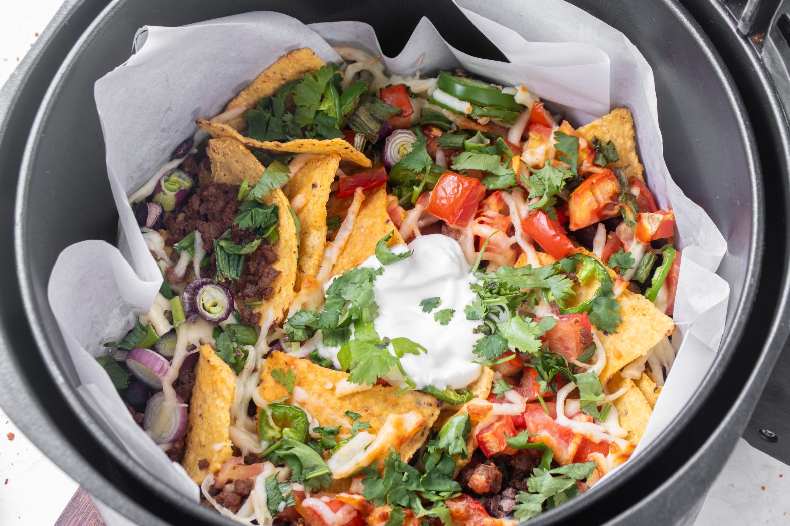 Nachos ingredients in a parchment-lined air fryer