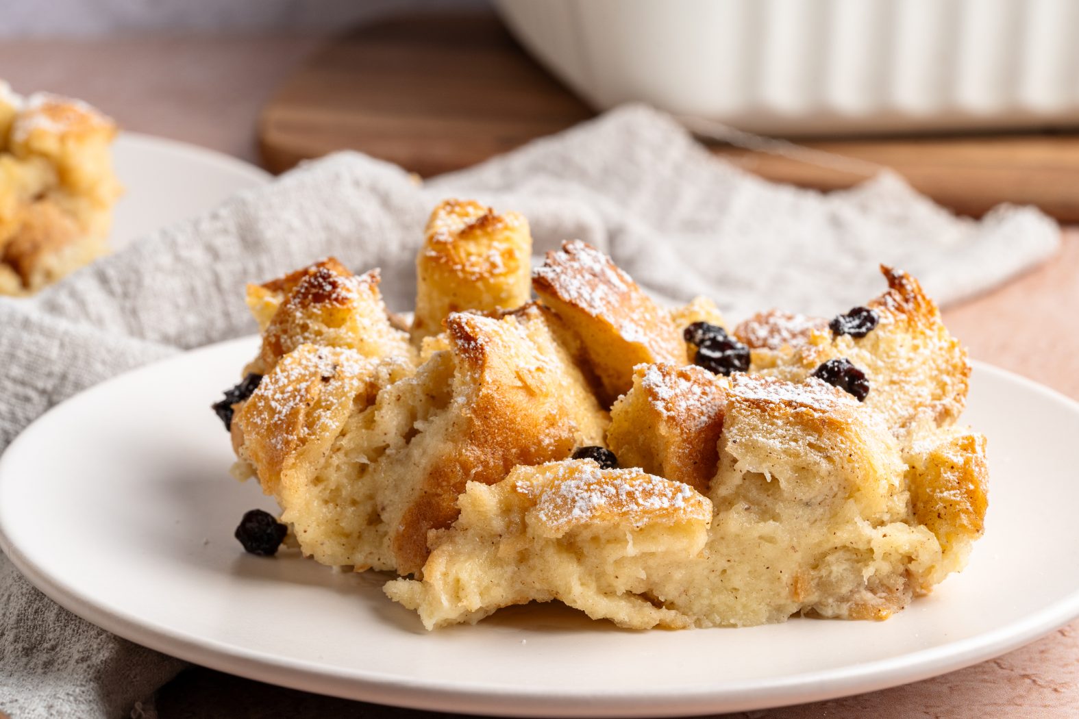 Side view of a slice of bread pudding on a white plate