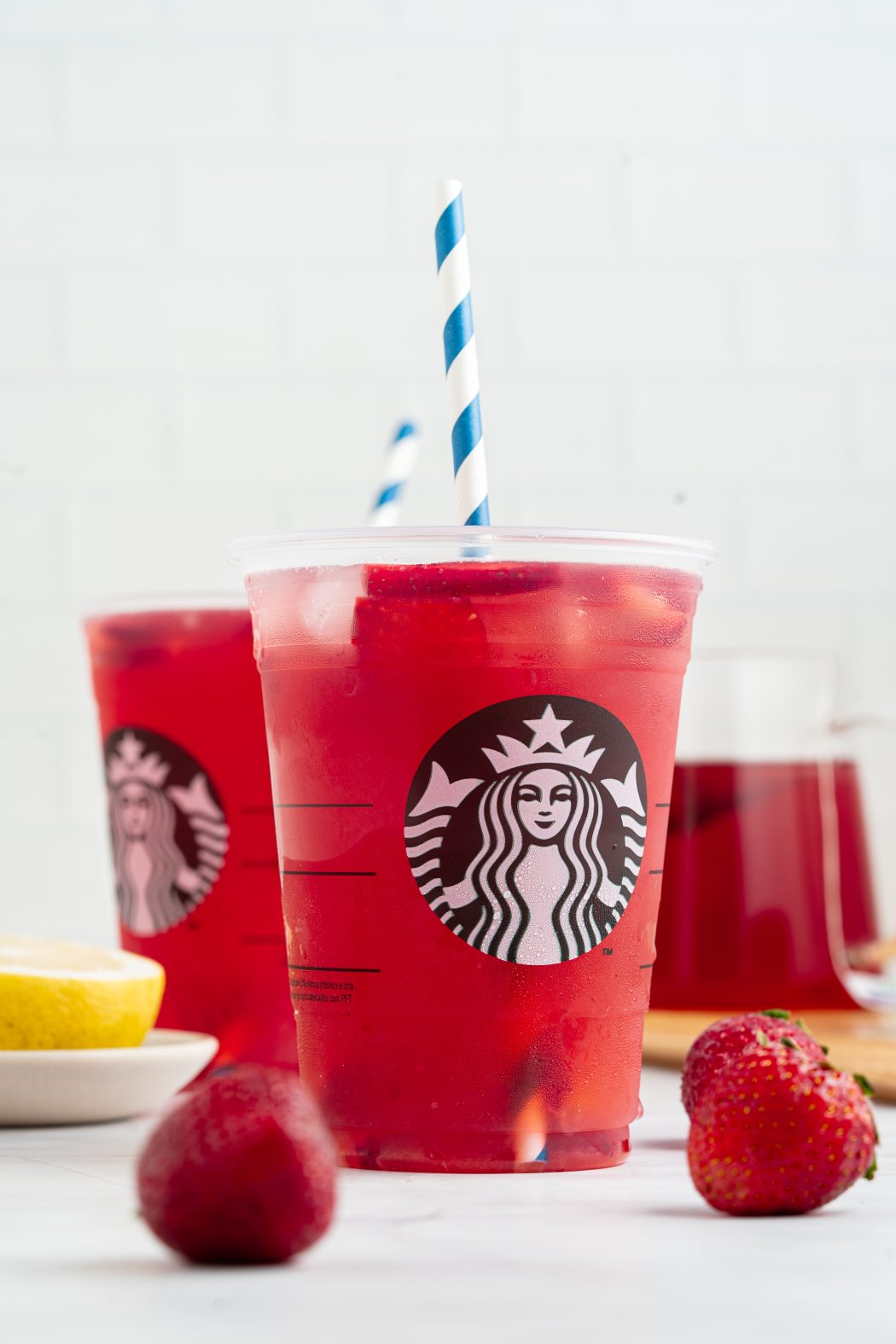 Strawberry Açaí Starbucks Refresher with fresh strawberries next to it