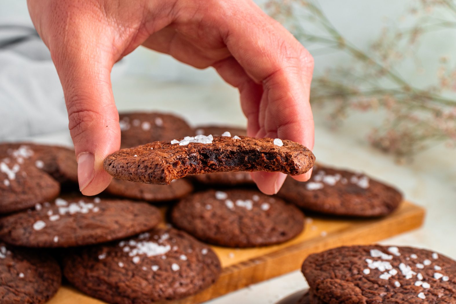 Hand holding a brownie cookie that has a bite taken out of it