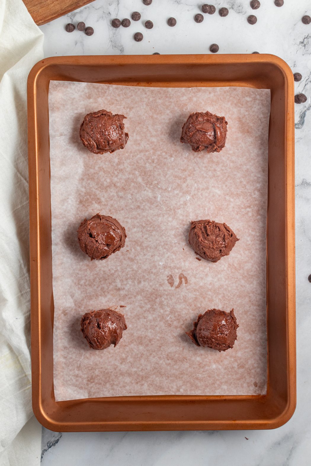 Cookie dough balls placed on parchment lined baking sheet